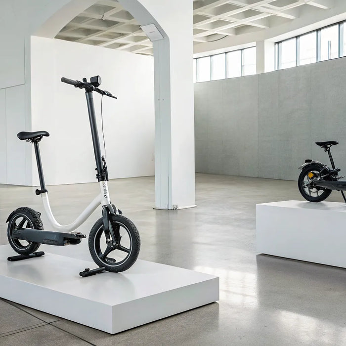 Collapsible personal transportation vehicles including folding bikes and electric scooters in a modern showroom.