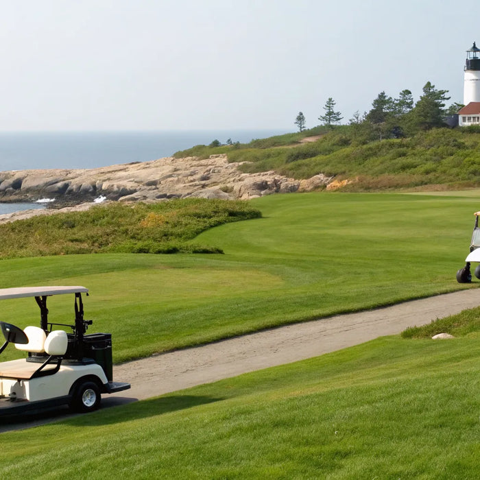 Six-passenger golf carts on a scenic coastal course in Maine with a lighthouse.