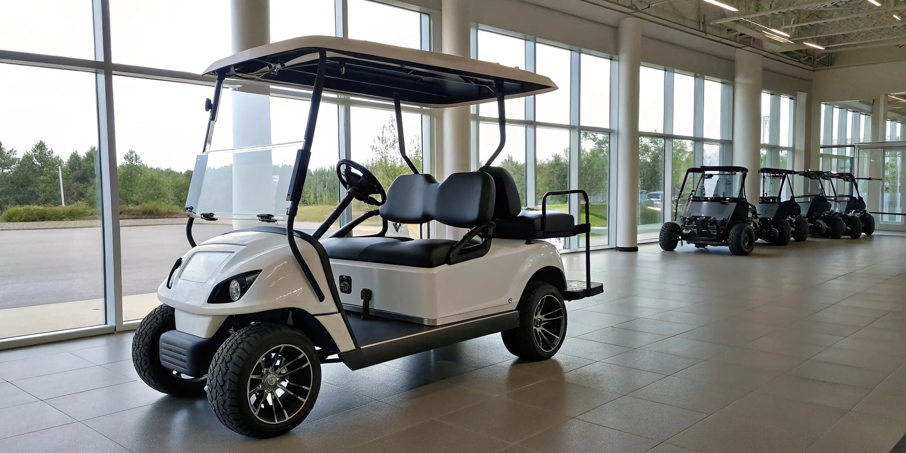 Modern white golf cart with black seats on display in a showroom.