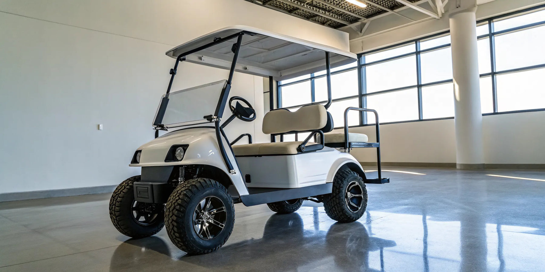 A refurbished electric golf cart with custom seats and wheels on display at a dealership.