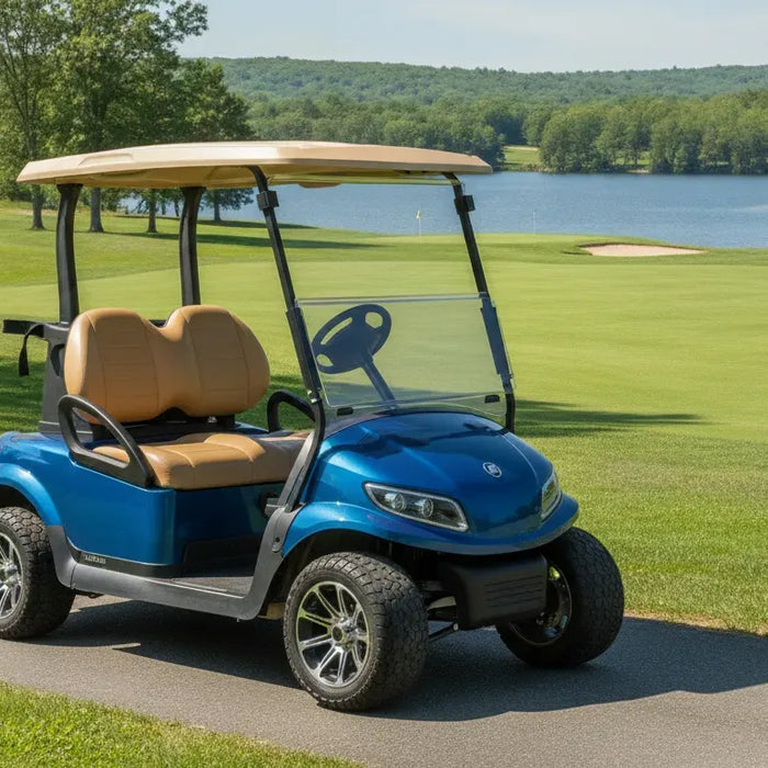 A sleek modern metallic blue lithium golf cart parked on a paved path next to a lush green New England golf course under bright sunny skies.