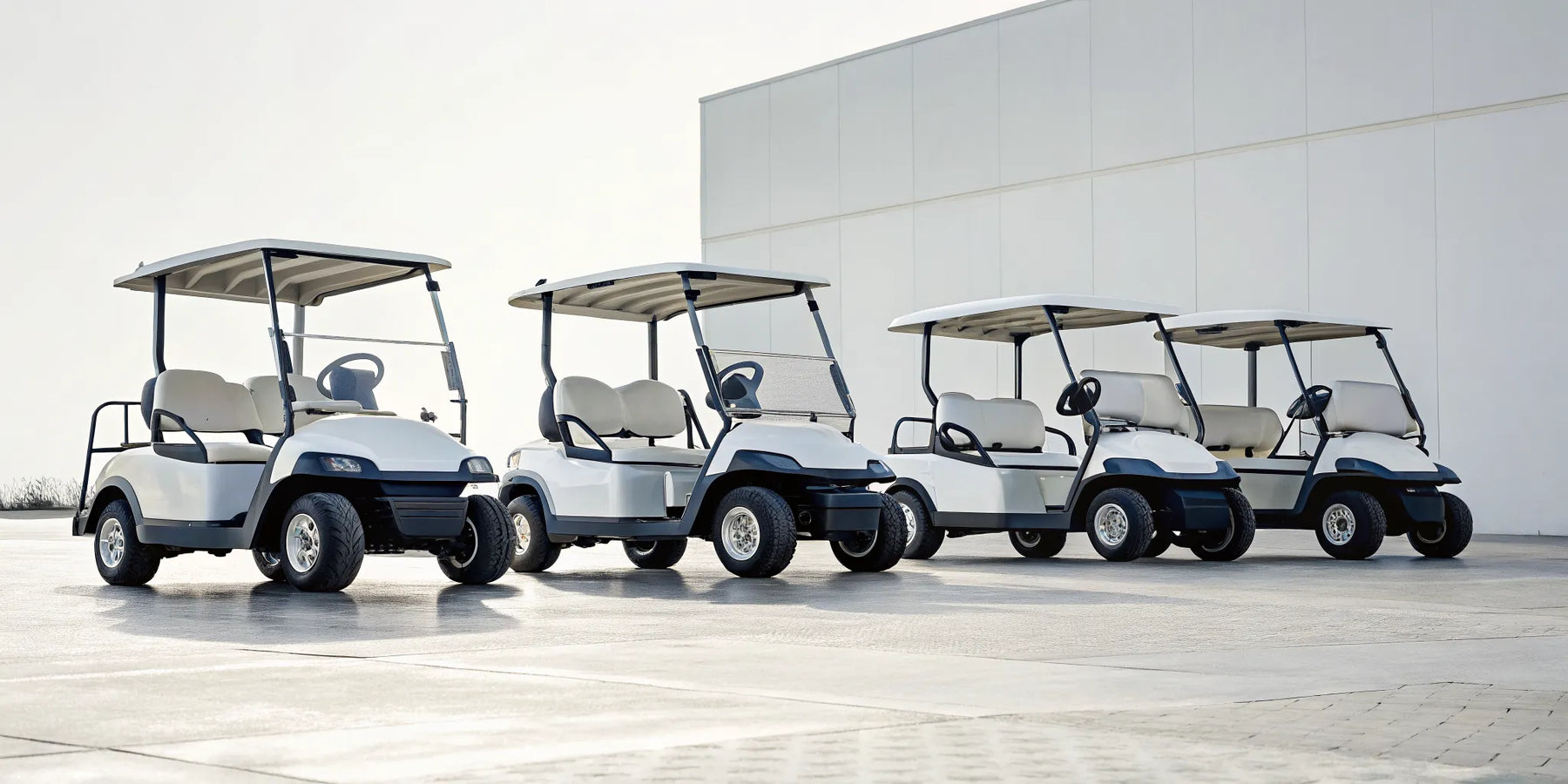 Four different 4-seat forward-facing golf carts parked side-by-side.